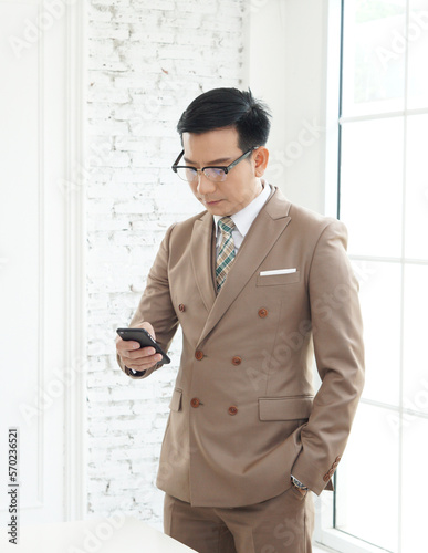 CEO Mature business man in formal clothing wearing spectacles using mobile phone. Serious businessman using smartphone at work. Manager in suit using cellphone in a modern office.