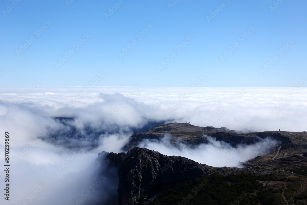 Above the clouds in Madeira, with rocky mountain scenery and blue sky above.