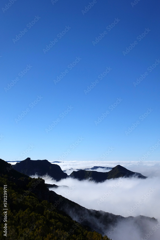 Above the clouds in Madeira, with rocky mountain scenery and blue sky above.