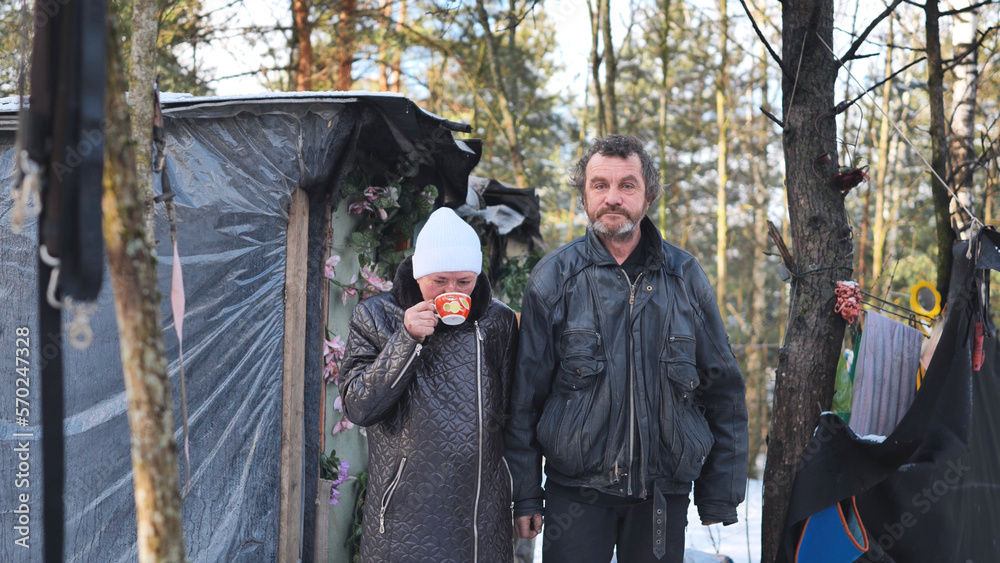 A homeless man and woman giving an interview in the winter in the woods.