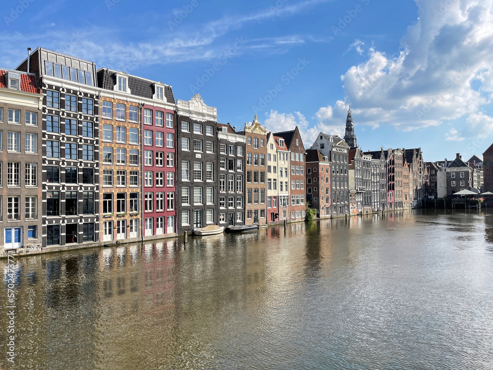 Gracht canal with typical old houses at Damrak in Amsterdam, Netherlands
