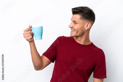 Young caucasian man holding cup of coffee isolated on white background with happy expression