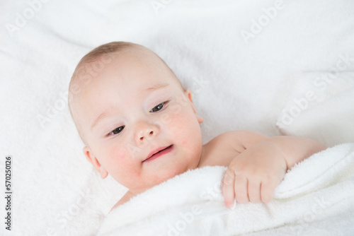 Happy little baby in white towels after bath