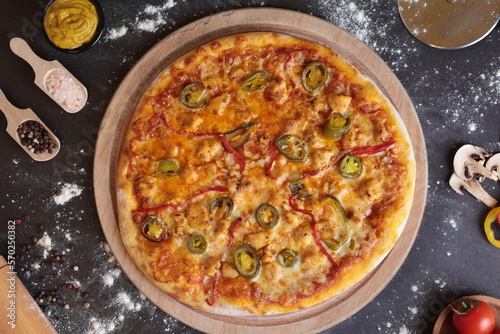 Pizza with jalapeno peppers, green peppers and capia peppers. It has supplies with it. top angle 