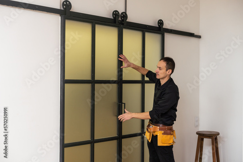 A handsome young man installing Double Sliding Patio Door in a new house construction site © Angelov