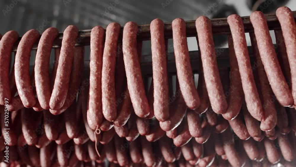 The production technology of sausage and smoked meat. Meat delicacies on the metal frame. Appetizing smoked. Meat Factory. Rows of ham