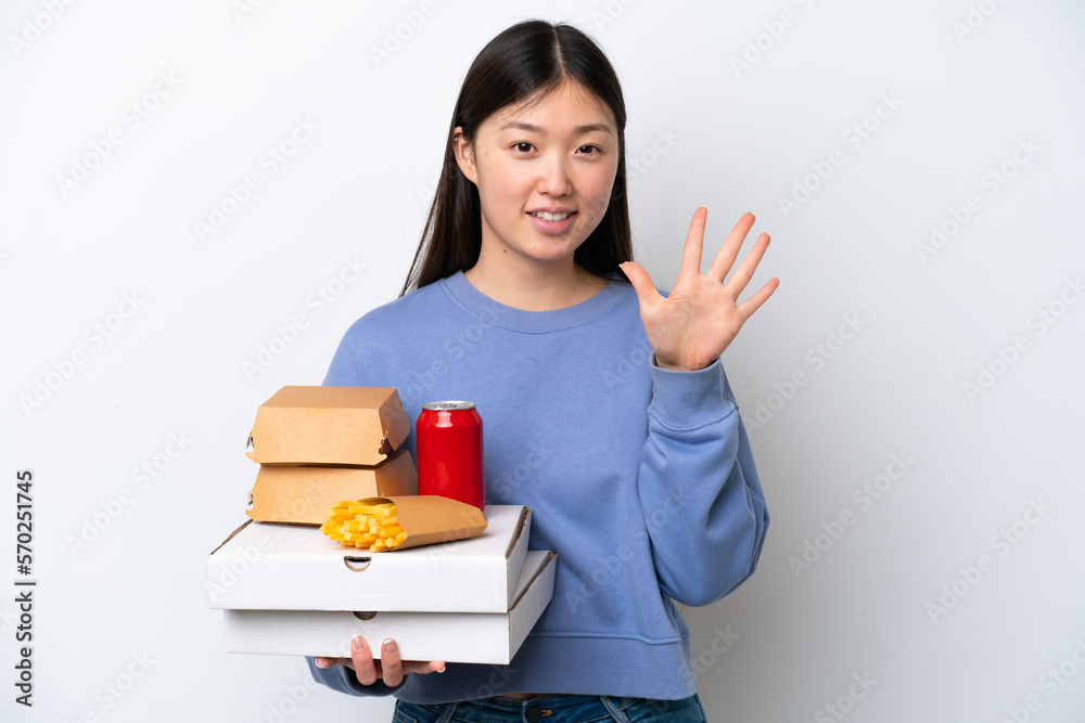 Young Chinese woman holding fast food isolated on white background counting five with fingers Young Chinese woman holding fast food isolated on white background counting five with fingers