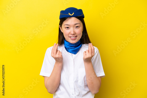 Airplane Chinese woman stewardess isolated on yellow background making money gesture