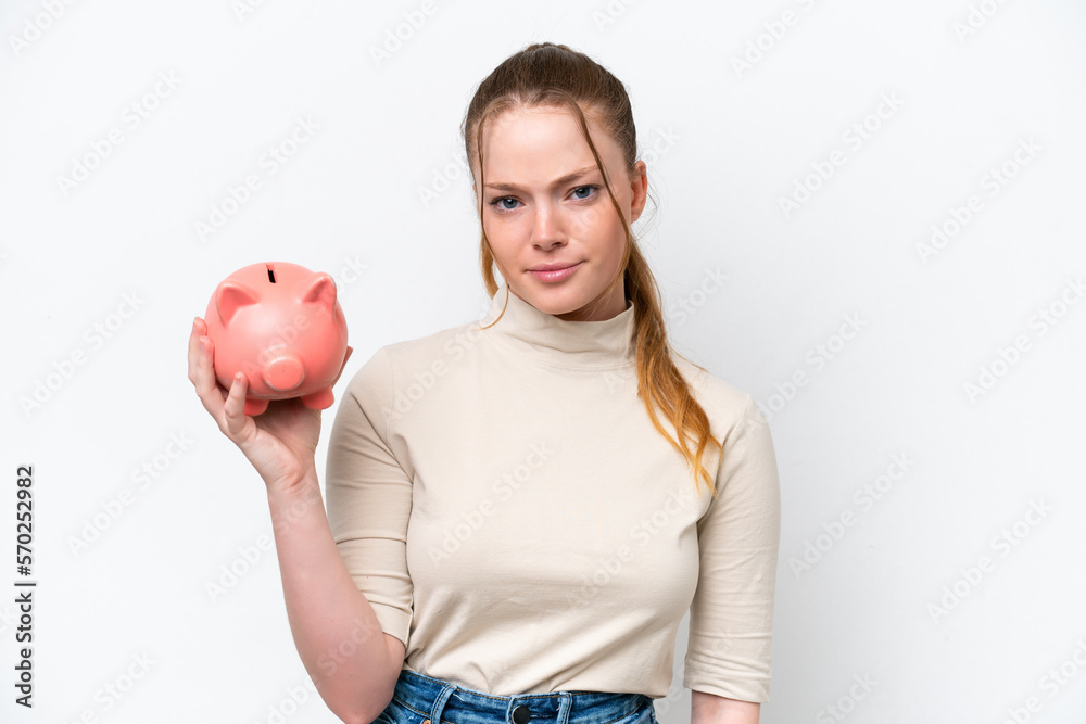 Young caucasian girl holding a piggybank isolated on white background with sad expression Young caucasian girl holding a piggybank isolated on white background with sad expression
