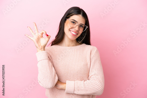 Young Italian woman isolated on pink background With glasses and doing OK sign