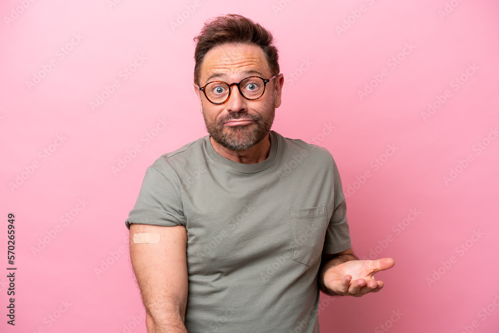 Middle age man wearing a band aids isolated on pink background making doubts gesture while lifting the shoulders Middle age man wearing a band aids isolated on pink background making doubts gesture while lifting the shoulders