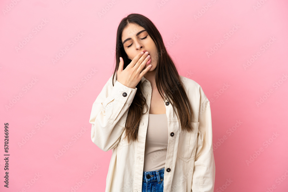 Young caucasian woman isolated on pink background yawning and covering wide open mouth with hand