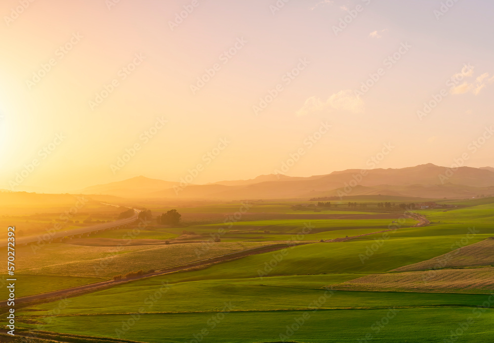 countryside sunset in green hills of spring fields with old castle farm and mountains on background of evening landscape countryside sunset in green hills of spring fields with old castle farm and mountains on background of evening landscape