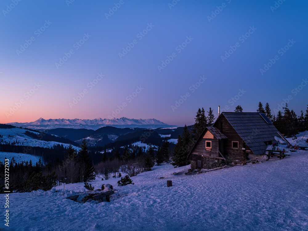 Mountain forest hut during purple ping orange sunset winter snow