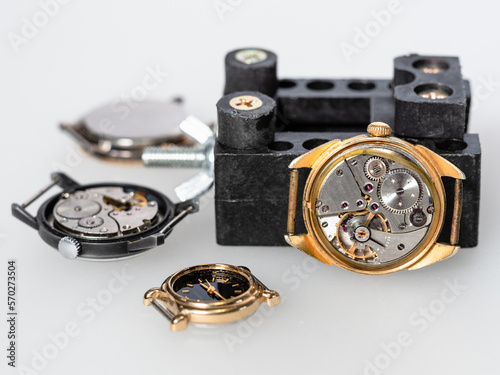 open yellow mechanical watch and old watches on white board in watchmaker workshop