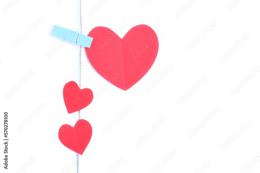 Red paper heart hanging on jute rope with wooden clothespins isolated on white background	