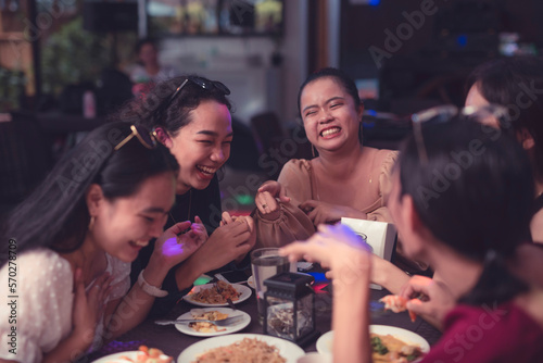 Five girl friends making fun of each other while talking about the funny moments they had in the past. Get together with long time buddies in a restaurant. Good company with colleagues.