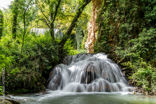 Cascade of multiple waterfalls in the middle of nature surrounded by trees and green vegetation.