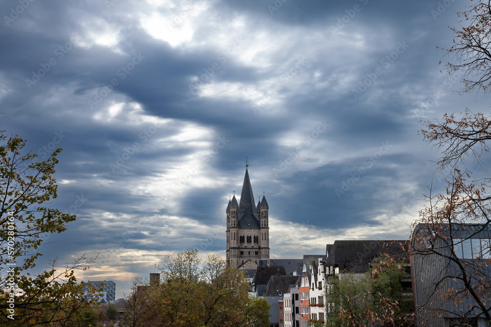 Main tower of the Gross Sankt Martin Kirche seen from afar in a cologne landscape during a cloudy afternoon. The Great Saint Martin Church is a Roman catholic medieval church in Cologne, Germany.