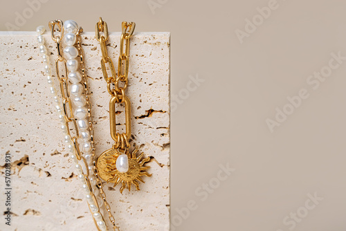 Trendy jewelry with chains, pearl necklace and pendant shapes moon and sun. Stylish golden bijouterie on the stone. Fashion accessories.