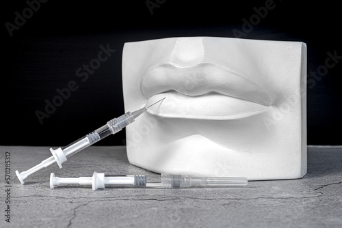 Injections. Antique plaster lips with medical syringes. Beauty and lip augmentation concept