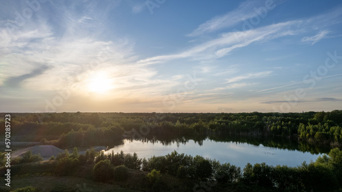 Aerial panoramic landscape over a winding forest road in Belgium, during sunset, drone shot. High quality photo