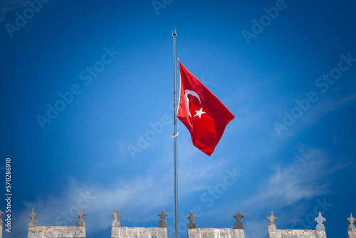 Turkish flag floating in the air in front of a blue sky in istanbul. Also called Turk Bayragi, the flag of turkey, red with a white crescent, is the national symbol of the republic of turkey.. photo
