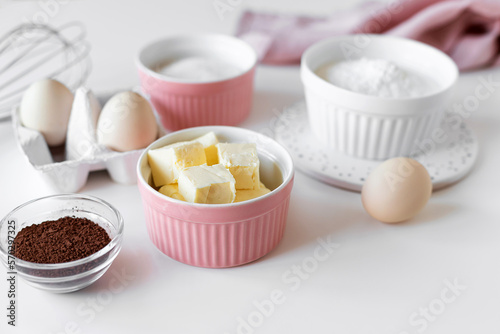Ingredients for baking cake, cupcakes or brownies on kitchen table. Bowls with butter, flour, sugar, cocoa powder and eggs. cooking class concept