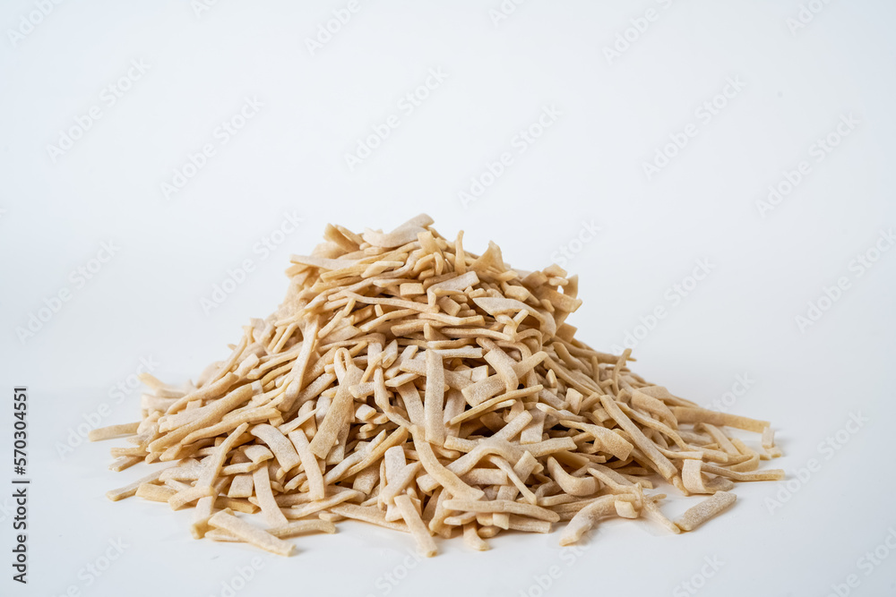 Uncooked traditional homemade egg noodles isolated on white background.