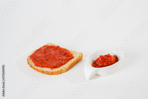 Chili tomato sauce with a slice of bread and small sauce cup isolated on white background.