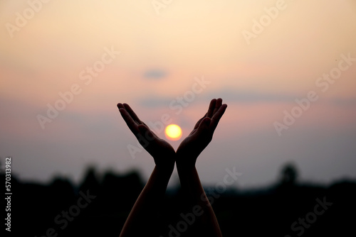 silhouette of human hand raised to make a wish, sunset background