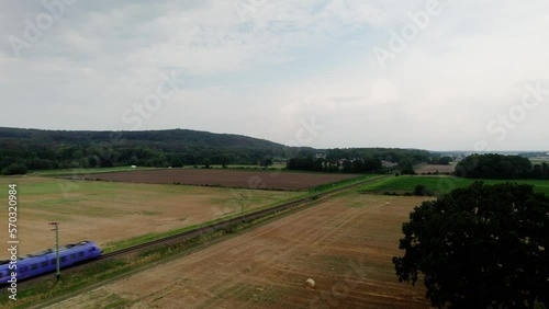 Electrified passenger train on single track travel through the Swedish landscape. Drone high angle aerial view