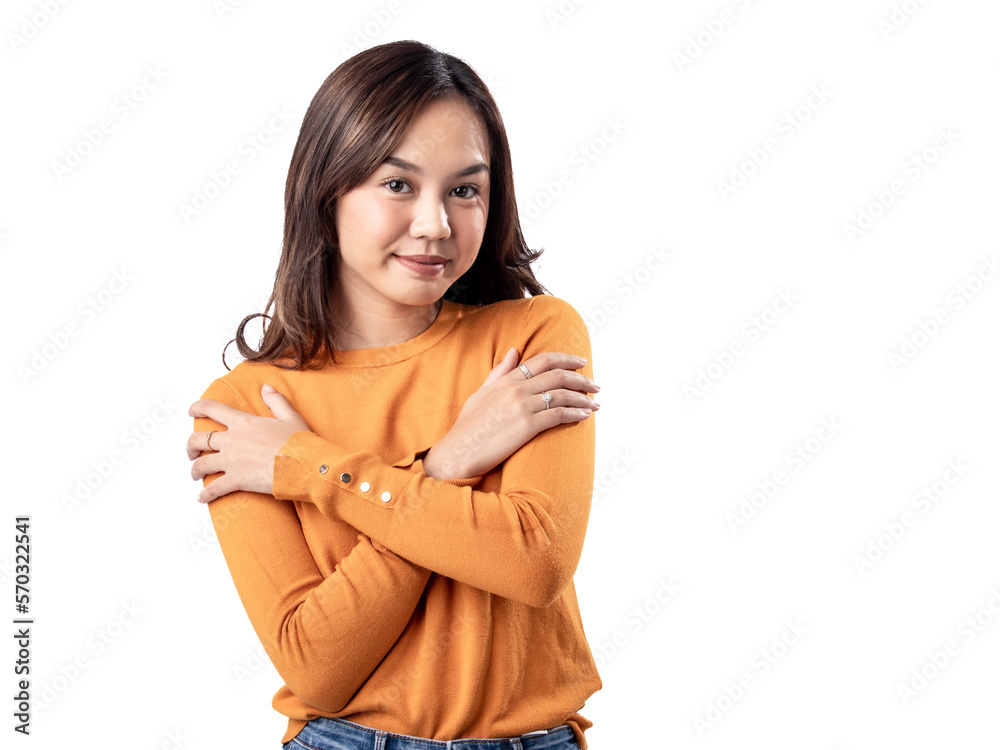 A portrait of a happy Asian Indonesian woman wearing an orange sweater, crossing her arms as if feeling cold, isolated on a white background. A portrait of a happy Asian Indonesian woman wearing an orange sweater, crossing her arms as if feeling cold, isolated on a white background.