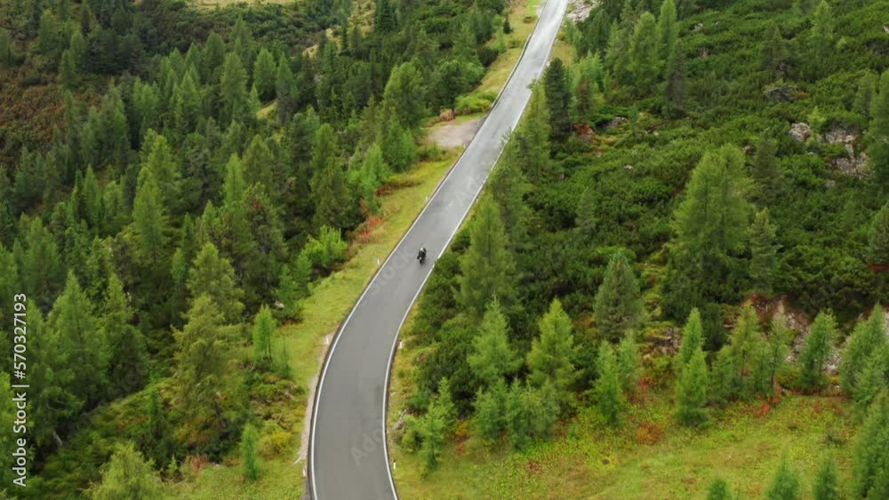 Motorcyclist rides on Snake Road and explores Alpine mountains nature. Famous Snake Road serpentine winds among mountain slopes with forests Motorcyclist rides on Snake Road and explores Alpine mountains nature. Famous Snake Road serpentine winds among mountain slopes with forests