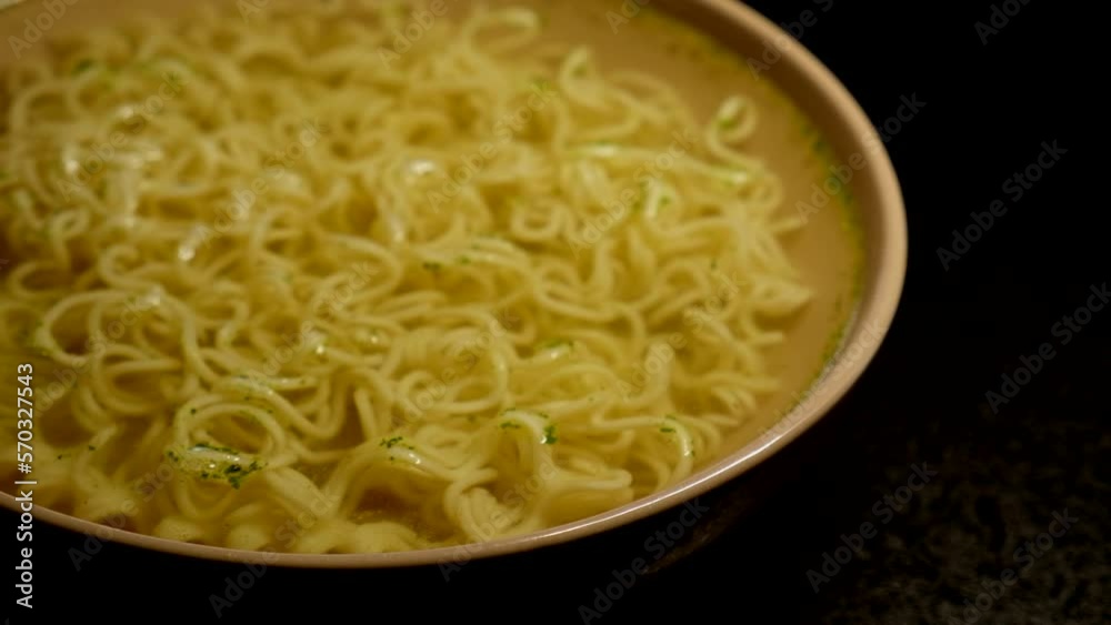 egg instant noodles are poured with water in a plate on a black background. top view egg instant noodles are poured with water in a plate on a black background. top view