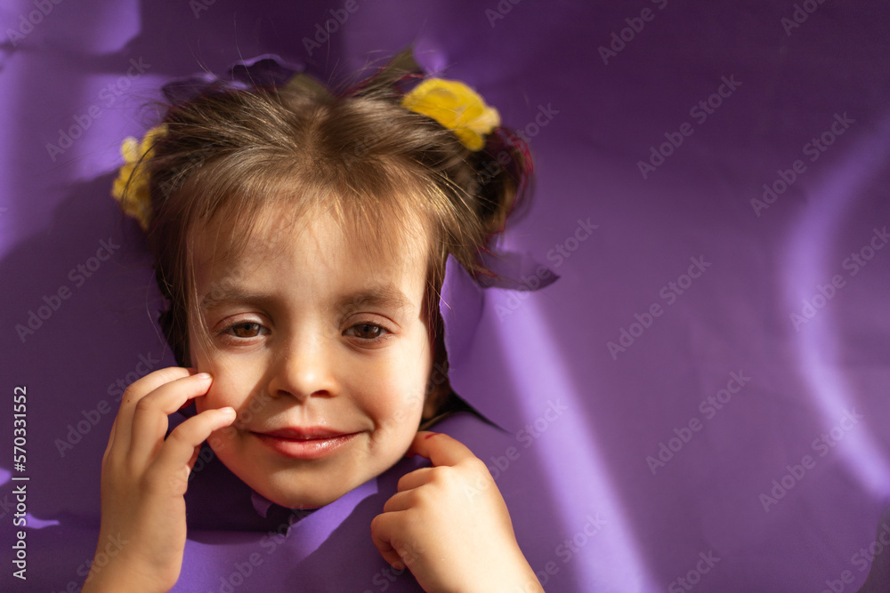 Cute girl smiling from hole in a paper