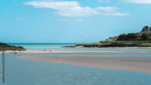 Clear sky over a sandy beach. A people on a sandy beach. Picturesque seascape of Ireland on a summer day. A copy space. People walking on beach