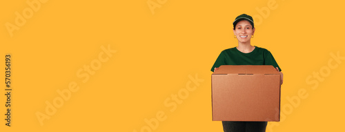 Banner size photo with copy space of a delivery woman holding a big box over yellow background. photo