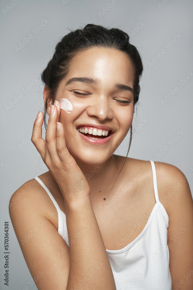 Content woman applying facial cream in studio Content woman applying facial cream in studio