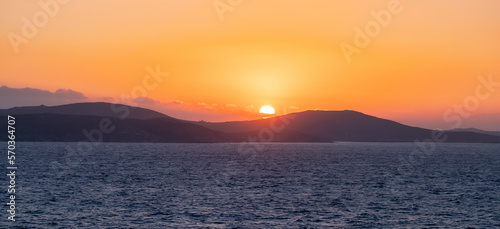 Rocky Island on Mediterranean Sea. Rinia near Mikonos, Greece, Europe. Nature Background. Sunrise Sky