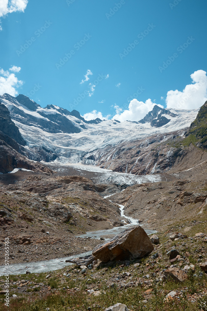 Landscape, mountain panorama, alpine meadows and mountain peaks in ice, a small house on the mountainside