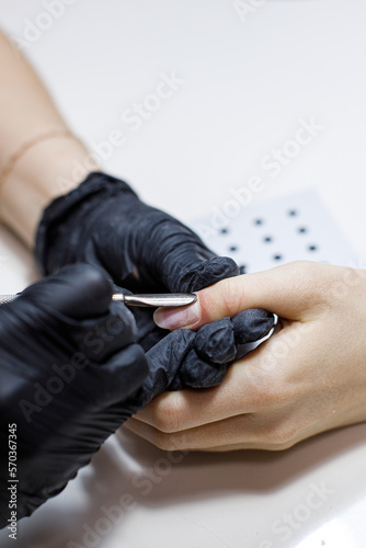 Closeup shot of a woman in a nail salon receiving a manicure by a manicurist. Woman getting nail manicure. Beauty and hand care concept.