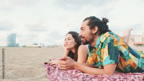 Man and woman talking and relaxing on blanket on the beach