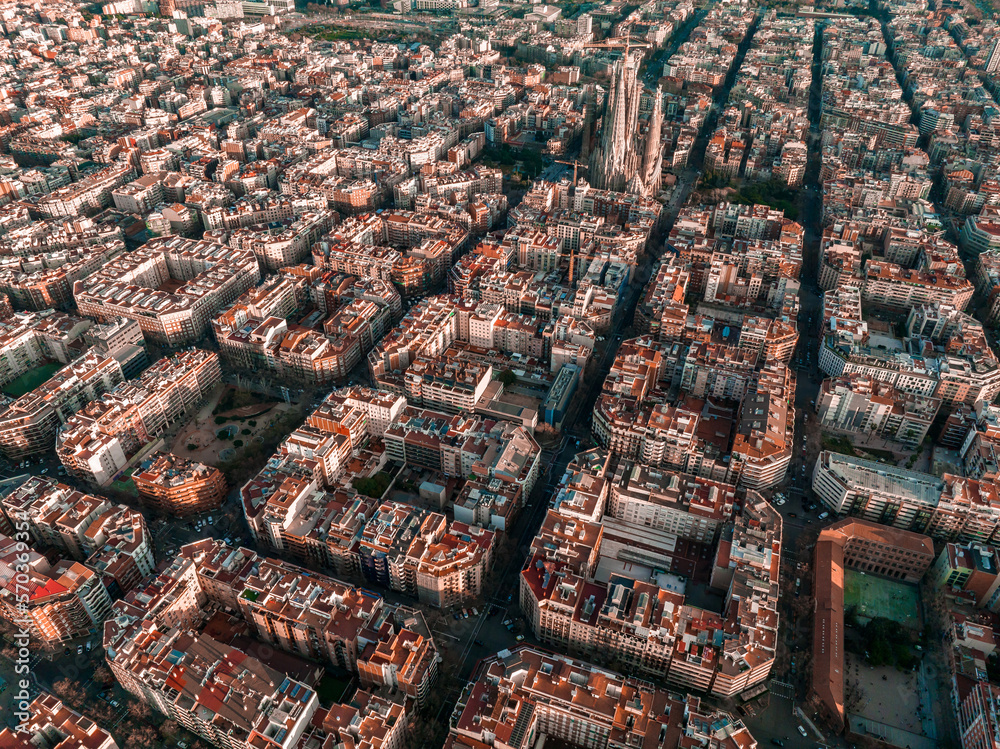 Obraz premium Aerial view of Barcelona City Skyline and Sagrada Familia Cathedral at sunset. Eixample residential famous urban grid. Cityscape with typical urban octagon blocks
