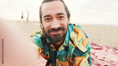Young man lies and relaxing on the beach and takes a selfie on a smartphone
