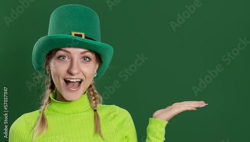 St. Patrick's Day leprechaun model girl in green hat, funny clover shaped sunglasses, isolated on green background and smiling, having fun. Patrick Day pub party, celebrating.
