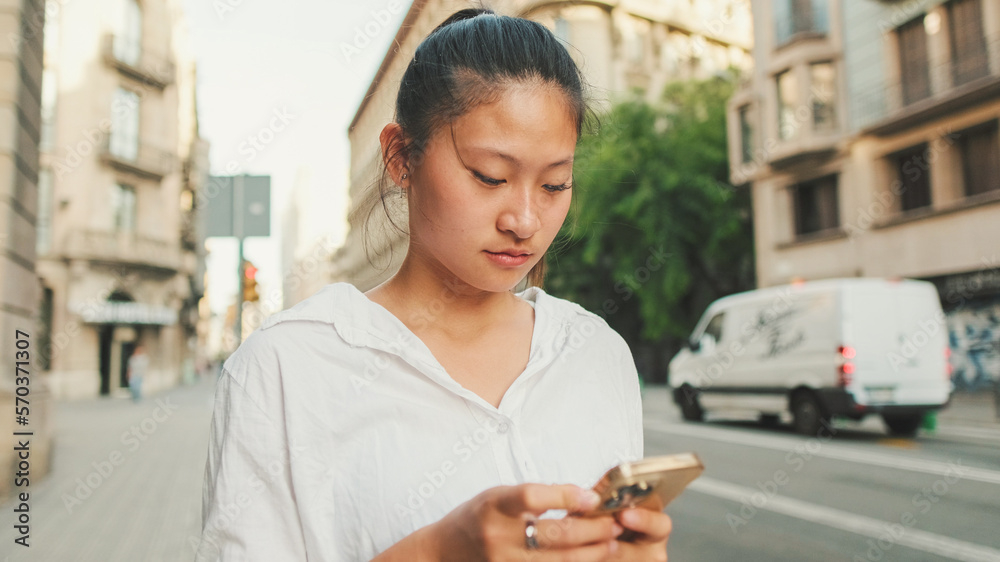Young smiling woman using mobile phone while standing next to the road