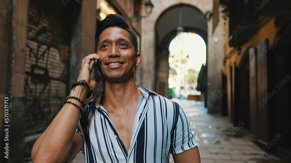 Young man tourist walks along narrow street of the old city and talks on mobile phone