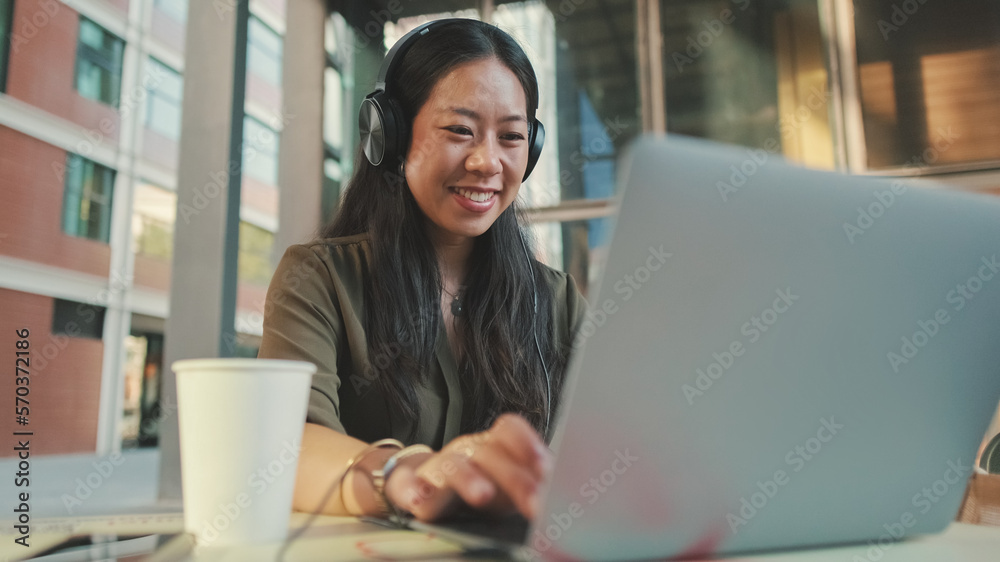 Young woman freelancer in headphones holding video conference on laptop