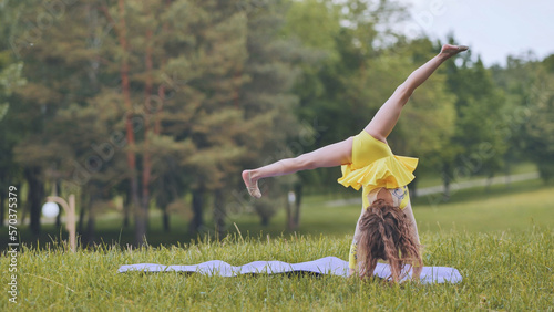 A little girl performs the elements of rhythmic gymnastics in the park.
